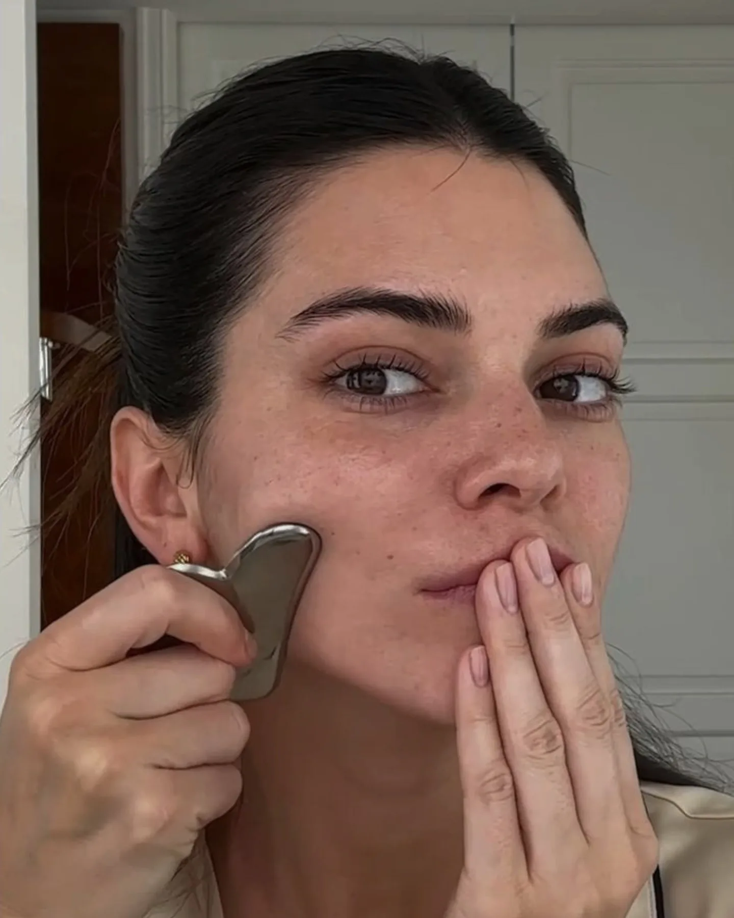 Devojka radi gua sha masažu lica.