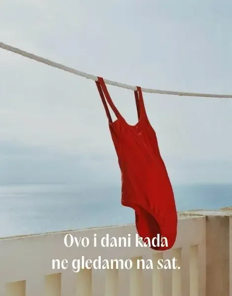 Crveni jednodelni kupaći kostim se suši na konopcu sa pogledom na plavo more