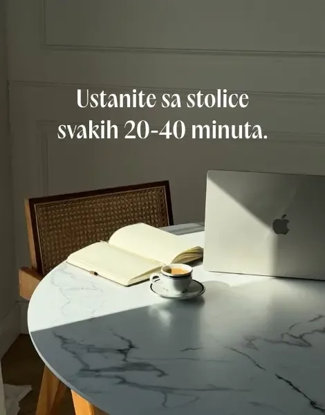 Otvorena sveska, šoljica kafe i zatvoren laptop na belom mermernom stolu obasjanom suncem