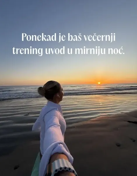Žena trči na peščanoj plaži dok sunce zalazi na horizontu iznad mora